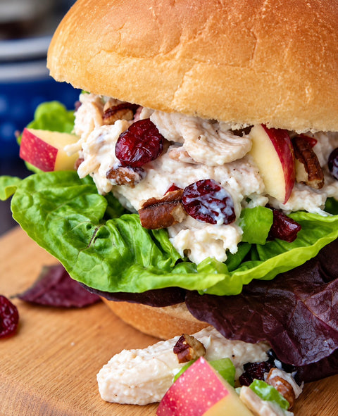 Cranberry apple chicken salad sandwich on a bun with lettuce, pecans and fresh apple, made with SnS Dips Cranberry Apple Chicken Salad Mix